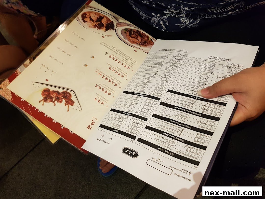 A person holding an open menu with Chinese and English text, featuring food items and prices.