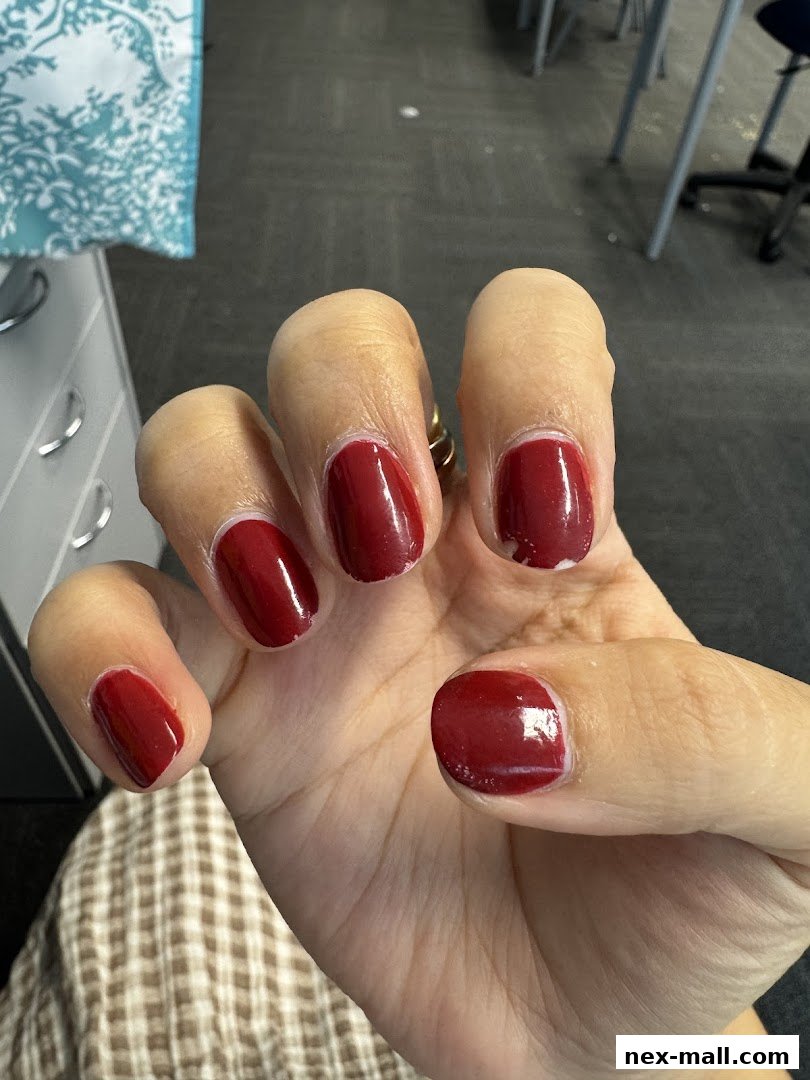 A close-up of a hand with freshly painted dark red nails.