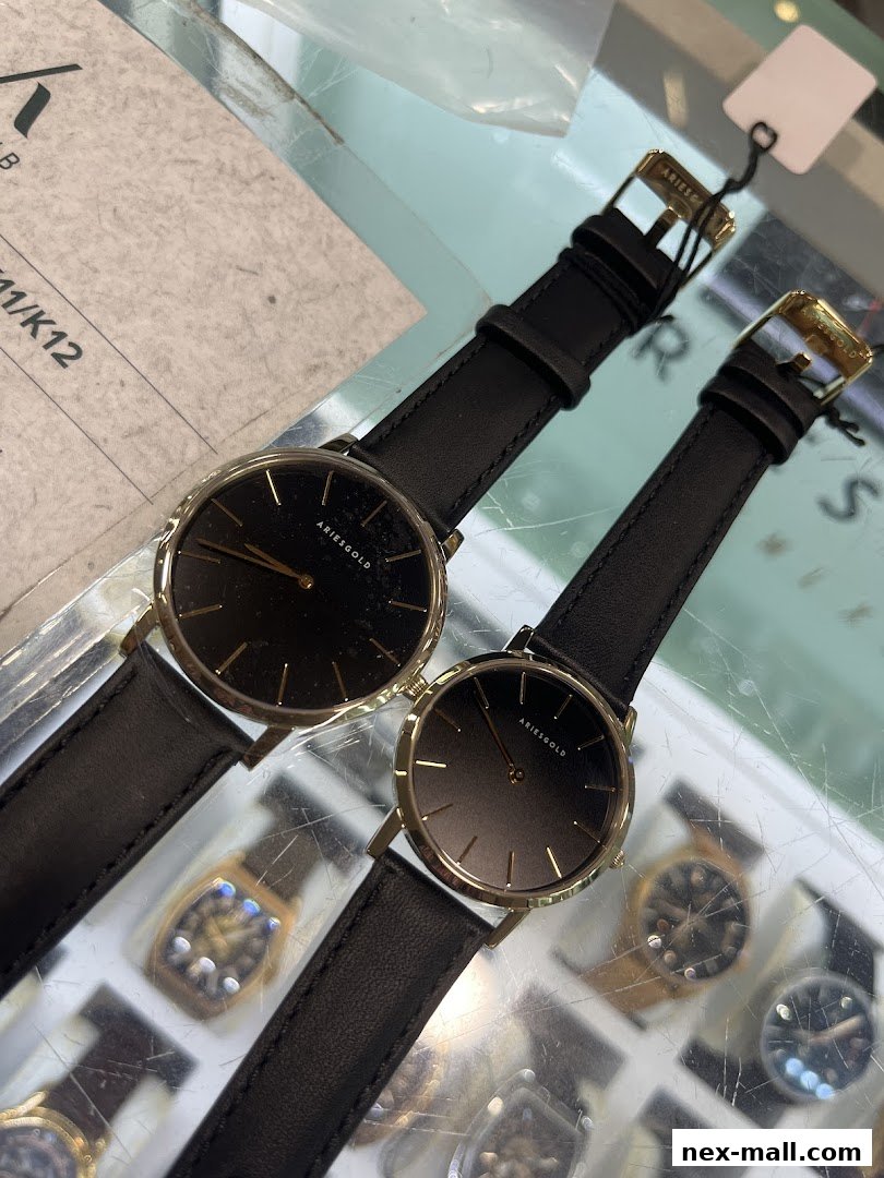 Two minimalist black dial watches with gold accents and black leather straps displayed.