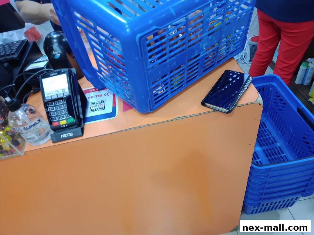 A checkout counter with a payment terminal, hand sanitizer, and shopping baskets.