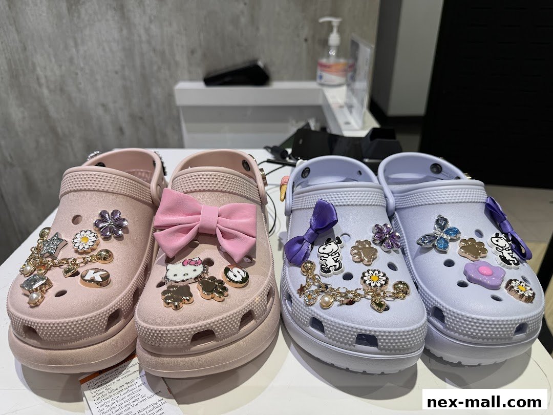 Four Crocs shoes decorated with various charms and bows, displayed on a table.