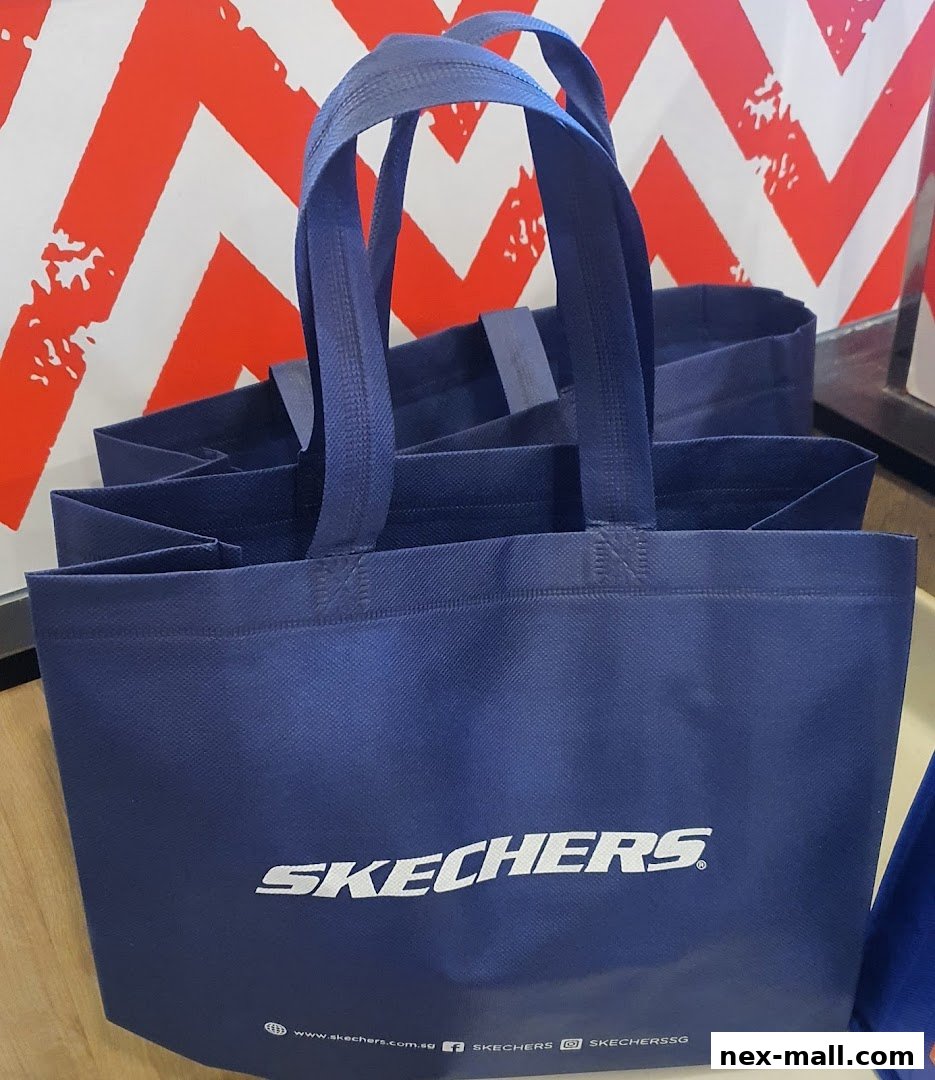 Navy blue Skechers shopping bags with white logo stacked in front of a red and white chevron pattern.