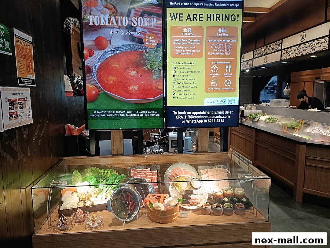 A display case filled with fresh ingredients for hot pot, with a digital menu board showing tomato soup.