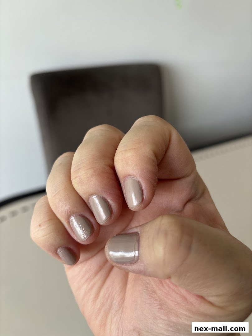 A close-up shot of a hand with neatly painted nude-colored fingernails.