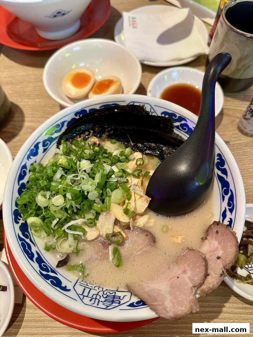 A steaming bowl of ramen with chashu pork, green onions, and a soft-boiled egg.
