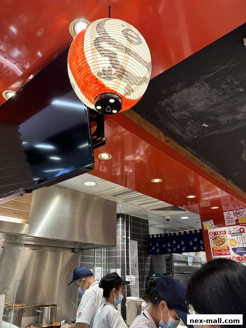 A Japanese restaurant interior with staff preparing food and a decorative lantern.