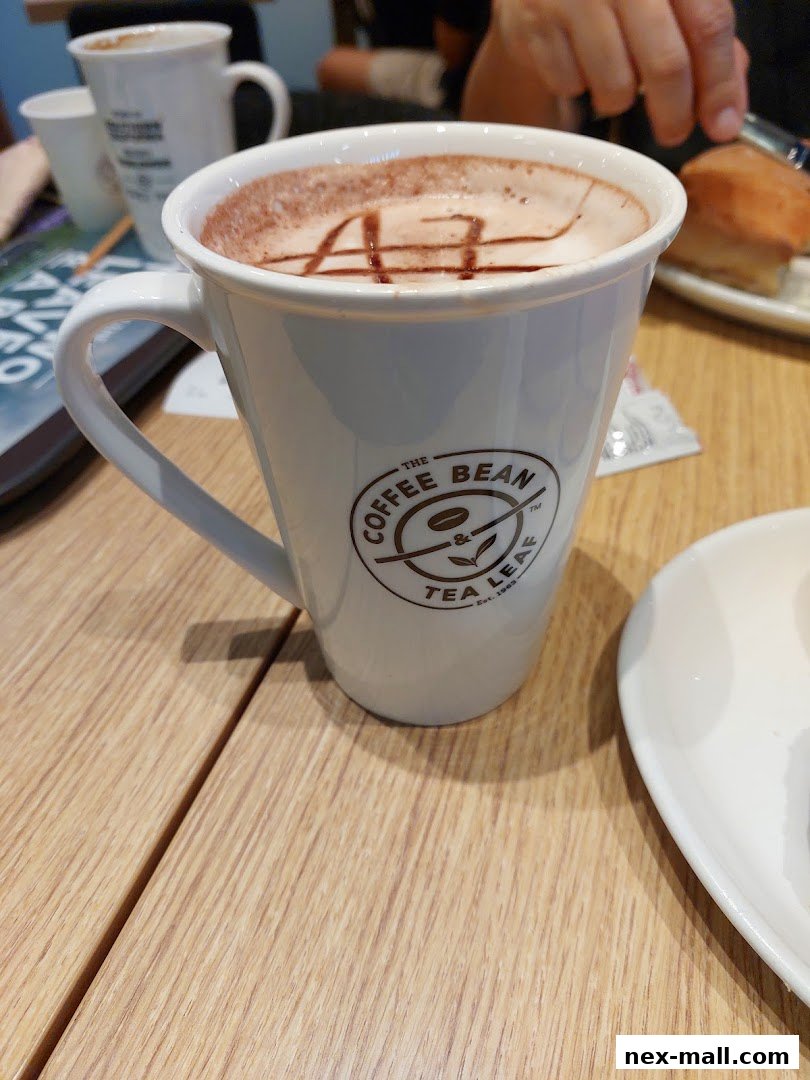 A close-up of a hot beverage in a white mug with the Coffee Bean & Tea Leaf logo.