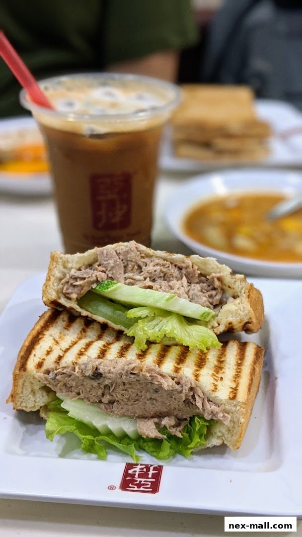 A close-up of a tuna sandwich with lettuce and cucumber, served with a drink.