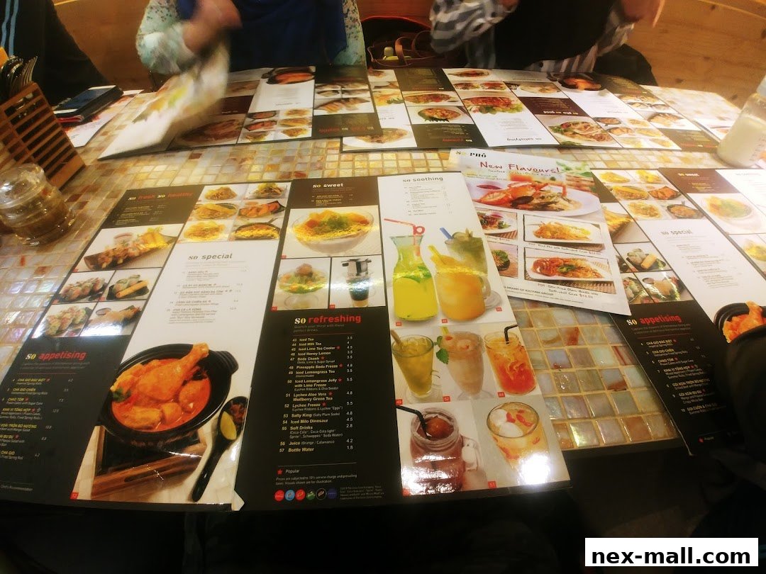 A table covered with menus from So Pho NEX, showcasing various dishes and drinks.