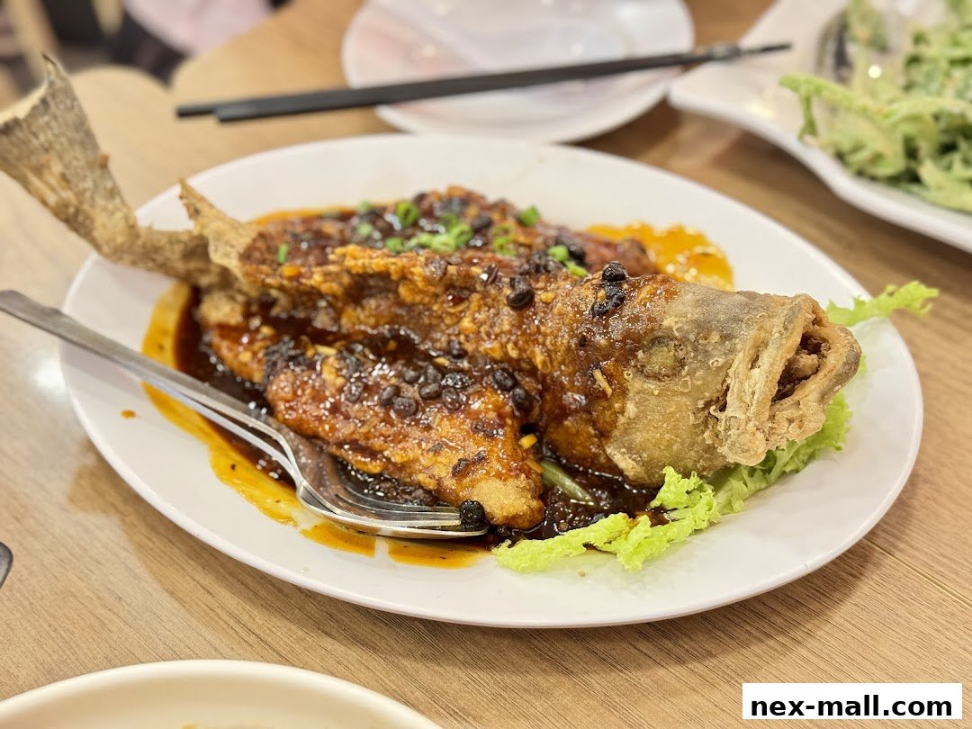 A whole fried fish coated in a savory sauce with black beans and scallions.
