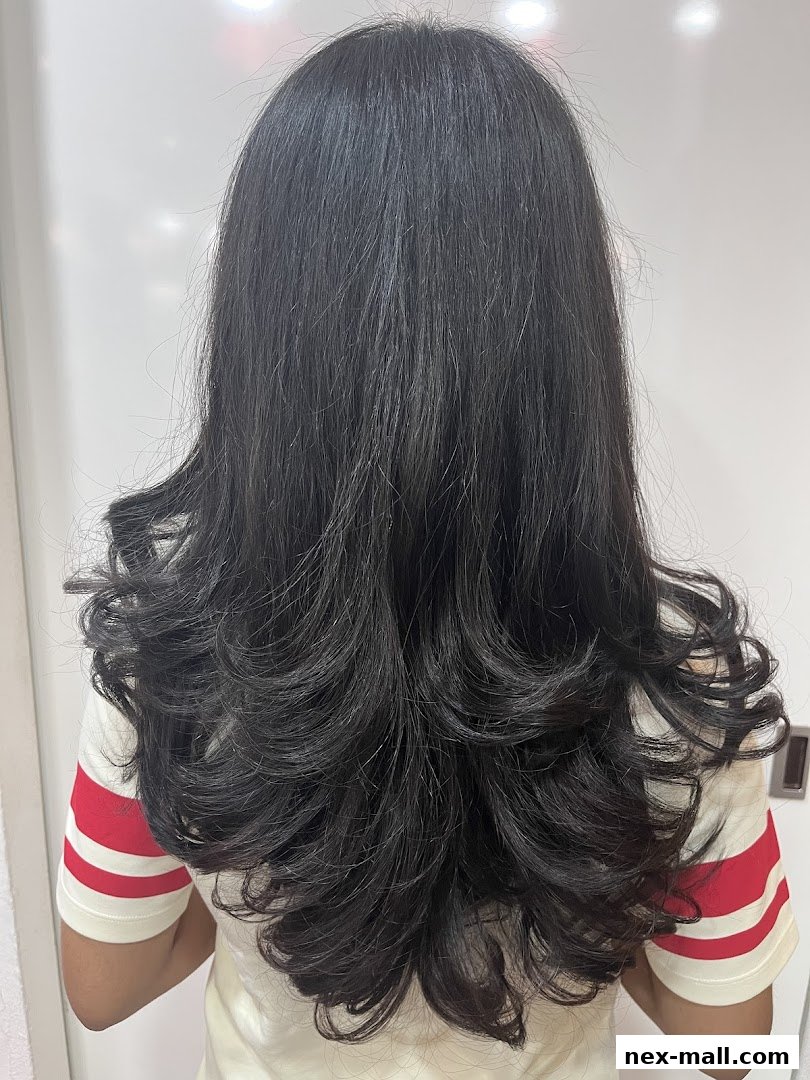 A person's back showcasing a voluminous, layered haircut with dark, wavy hair.