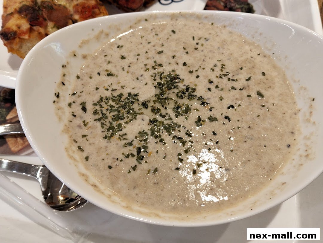 A close-up shot of a bowl of creamy mushroom soup topped with herbs.