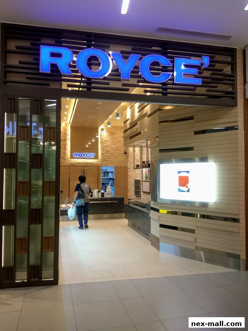 The entrance to a Royce shop with a prominent blue illuminated sign and a customer entering.
