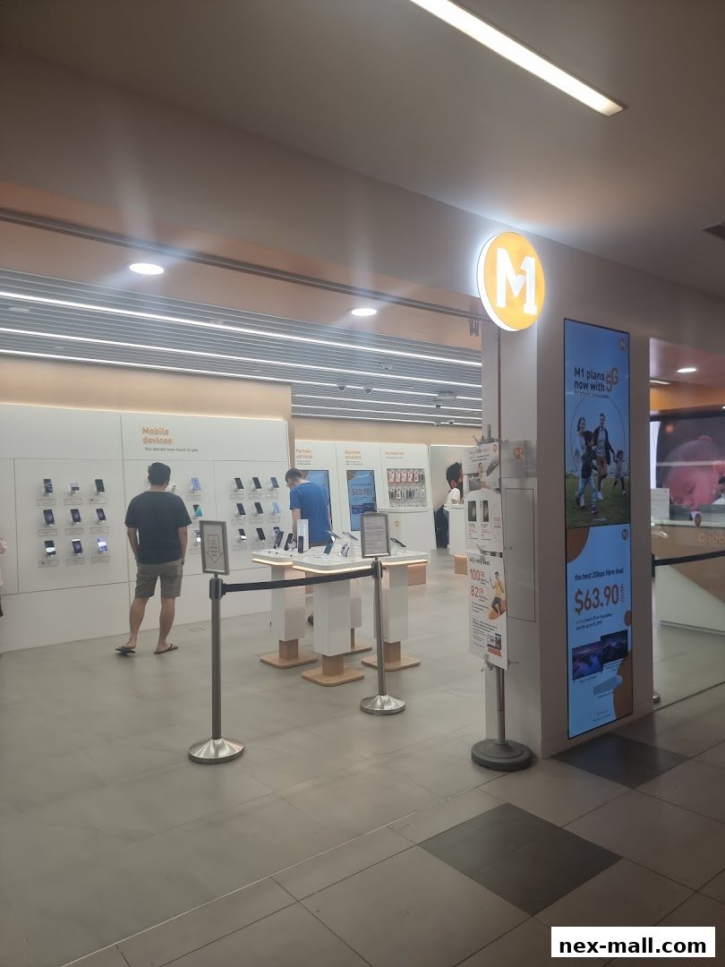 Interior of a modern M1 NEX phone shop with mobile devices on display and promotional signage.