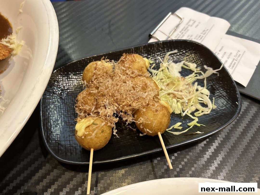 A plate of takoyaki with bonito flakes and a side of shredded cabbage.