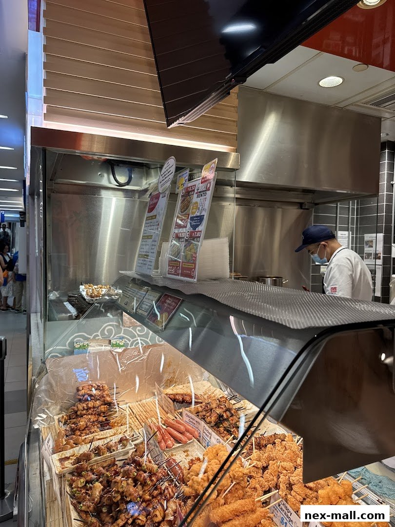 A display case filled with various skewers of grilled meat and fried snacks at TORI-Q.