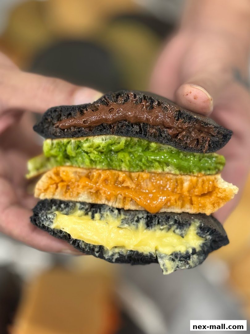 A close-up shot of a stacked pancake dessert with multiple colorful fillings.