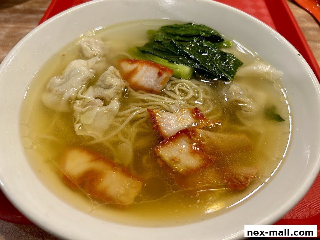 A close-up shot of a delicious bowl of wonton noodle soup with char siu pork.