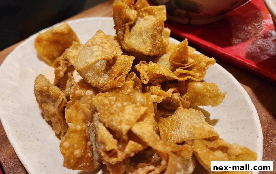 A close-up shot of crispy fried wontons served on a white plate.