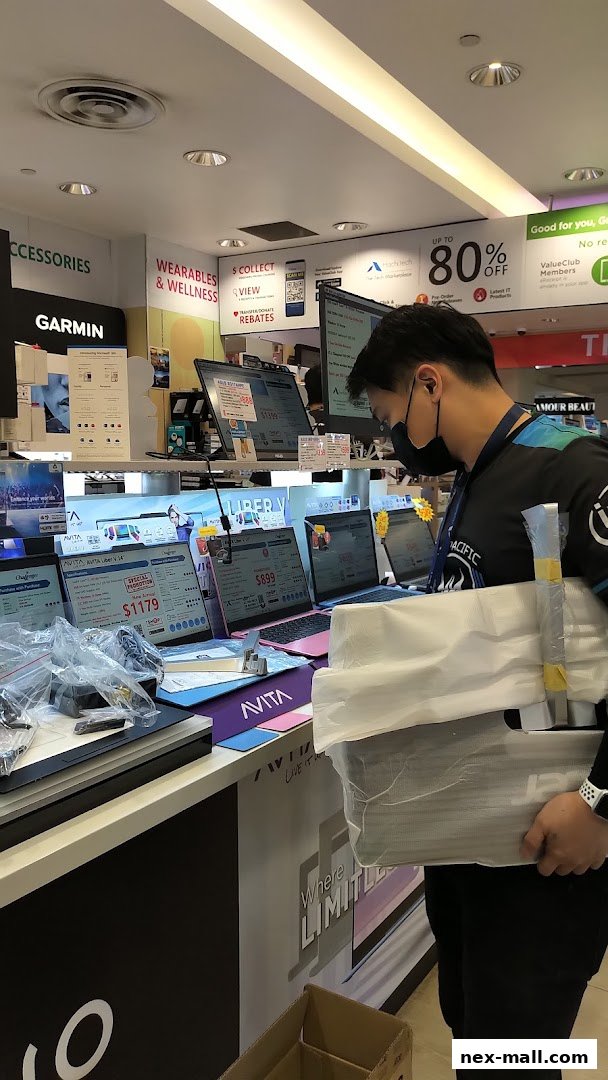 A customer browses laptops at Challenger NEX, with various models and promotions displayed.