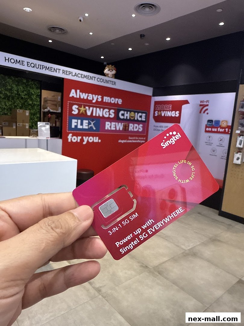 A hand holds a Singtel 3-in-1 5G SIM card in front of a retail store display.