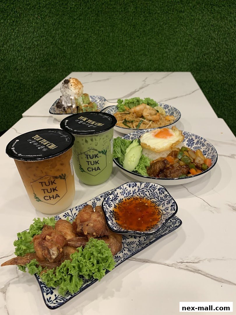 A spread of Thai dishes and drinks from Tuk Tuk Cha Treasures, including fried chicken wings, Pad Thai, and iced beverages.