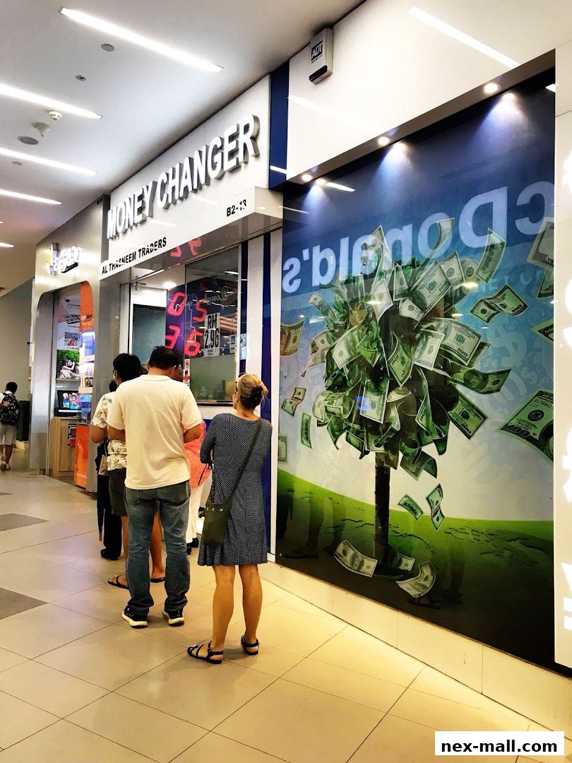 People queuing outside AL Thasneem Traders Money Changer with a money tree graphic on the window.