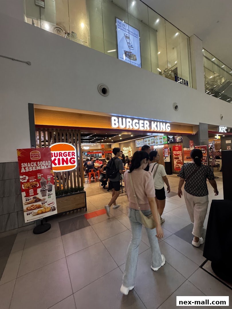 Burger King restaurant entrance with a promotional poster and people walking by.