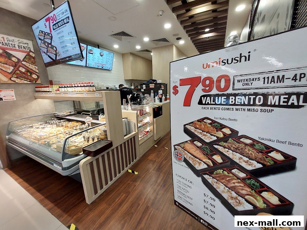 Interior view of a sushi shop with a display case of food and a promotional sign for bento meals.