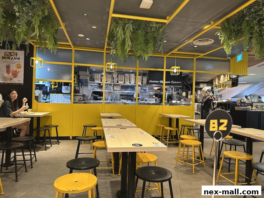 Interior of a Guzman y Gomez restaurant with yellow accents and hanging plants.