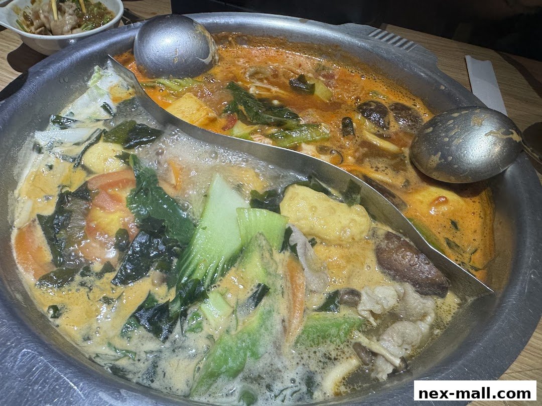 A split pot of hot pot with various ingredients like vegetables, mushrooms, and meat.