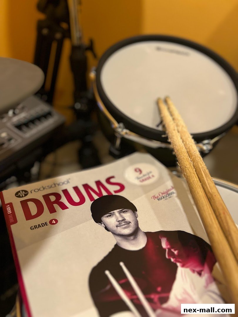 A drum kit with drumsticks and a Rock School Drums Grade 4 book.