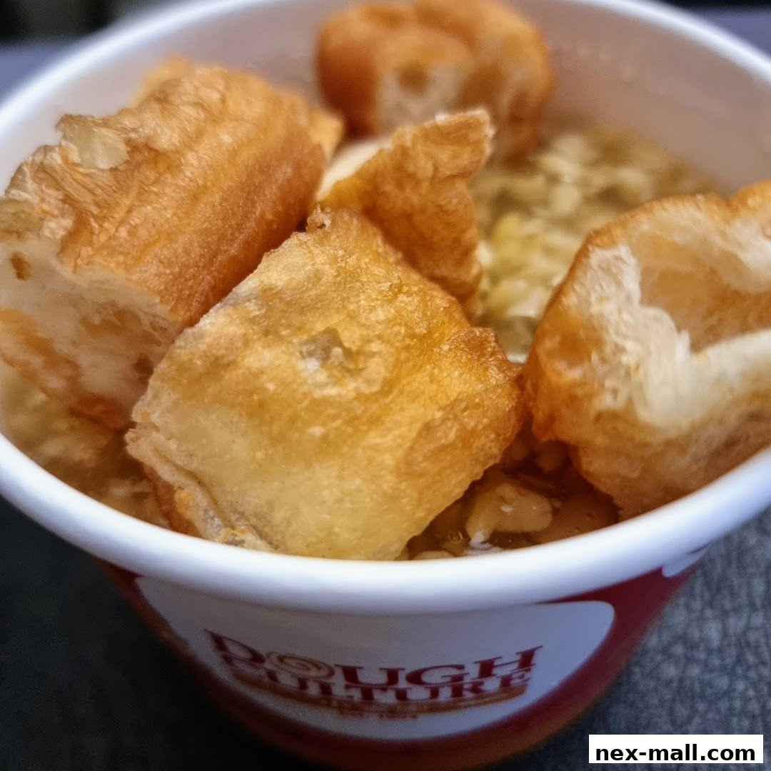 A close-up of a bowl of savory porridge topped with crispy fried dough sticks.