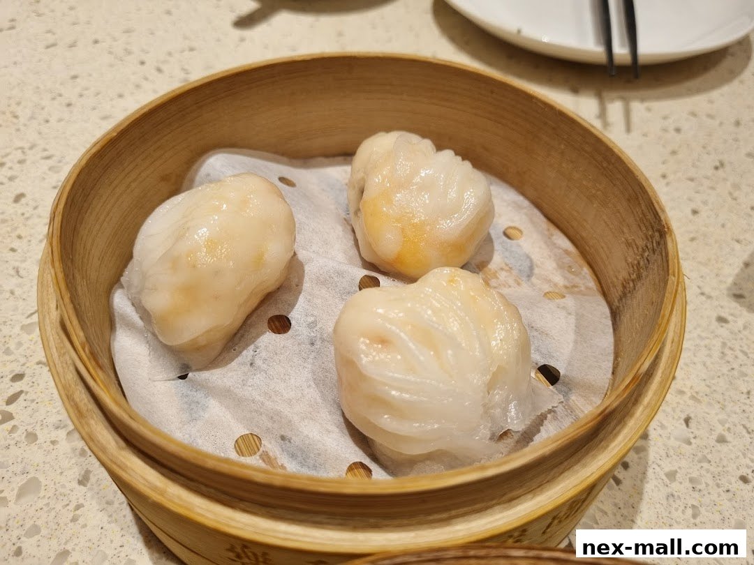 A close-up shot of three steamed shrimp dumplings in a bamboo steamer.