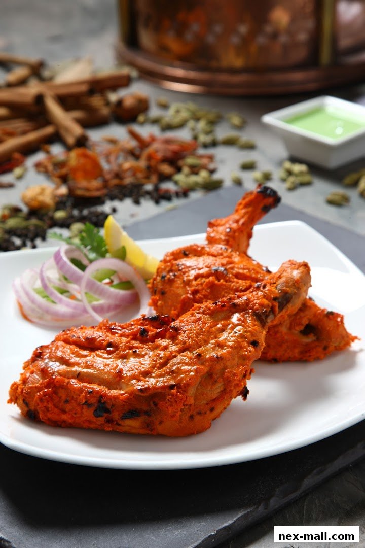 A plate of tandoori chicken drumsticks with sliced onions and a lemon wedge.