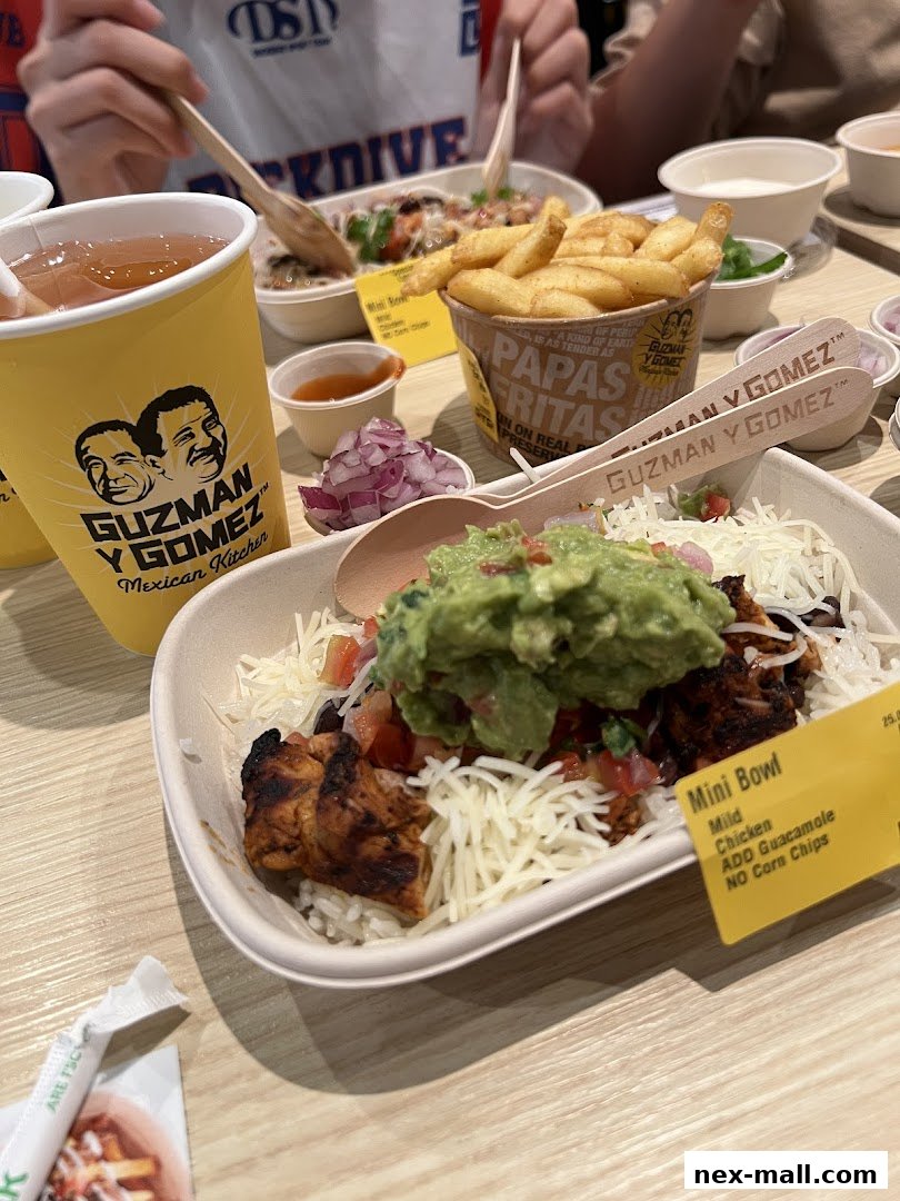 A close-up of a Guzman y Gomez meal with a mini bowl, fries, and a drink.