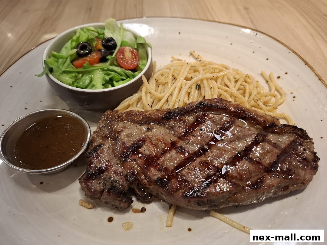 A grilled steak with spaghetti and a side salad served on a white plate.