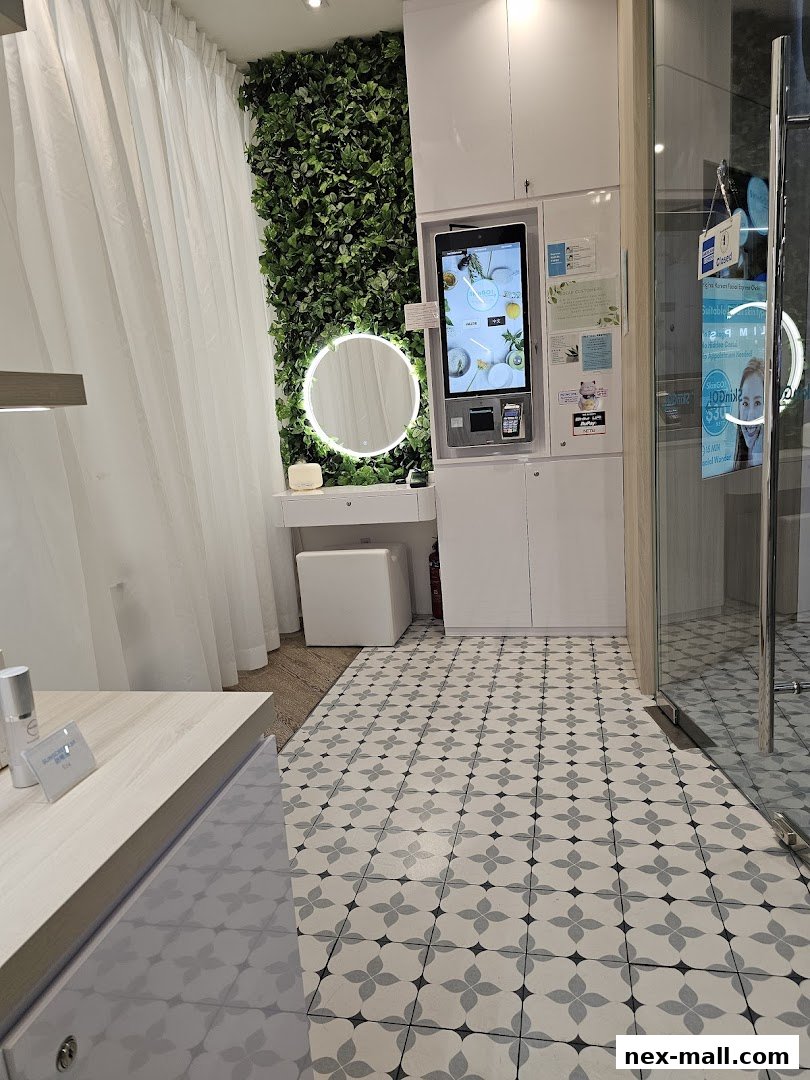 Interior of a modern beauty salon with a vanity, green wall, and digital kiosk.