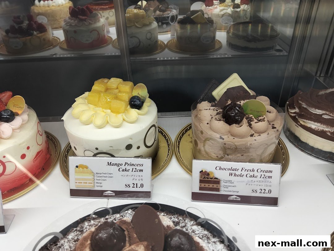A display of beautifully decorated cakes, including a mango and a chocolate fresh cream cake.