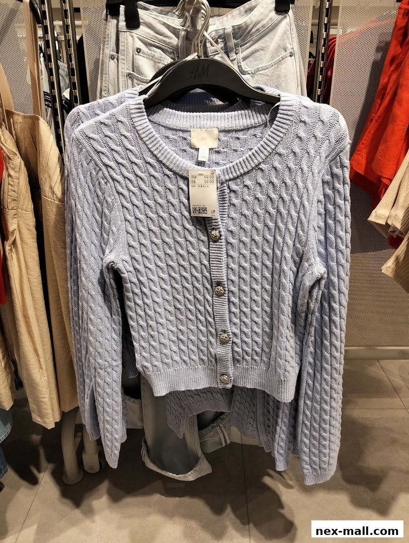 A light blue cable-knit cardigan with silver buttons is displayed on a hanger.