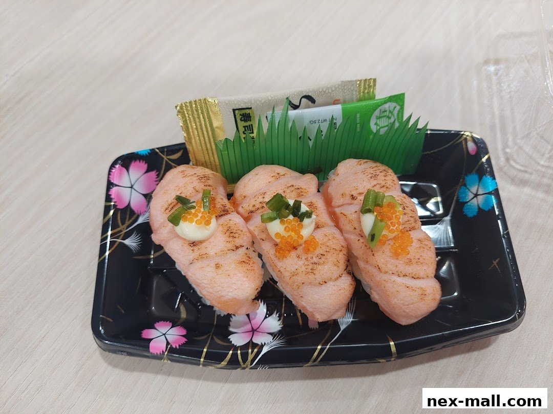 Three pieces of grilled salmon sushi with toppings on a black decorative plate.