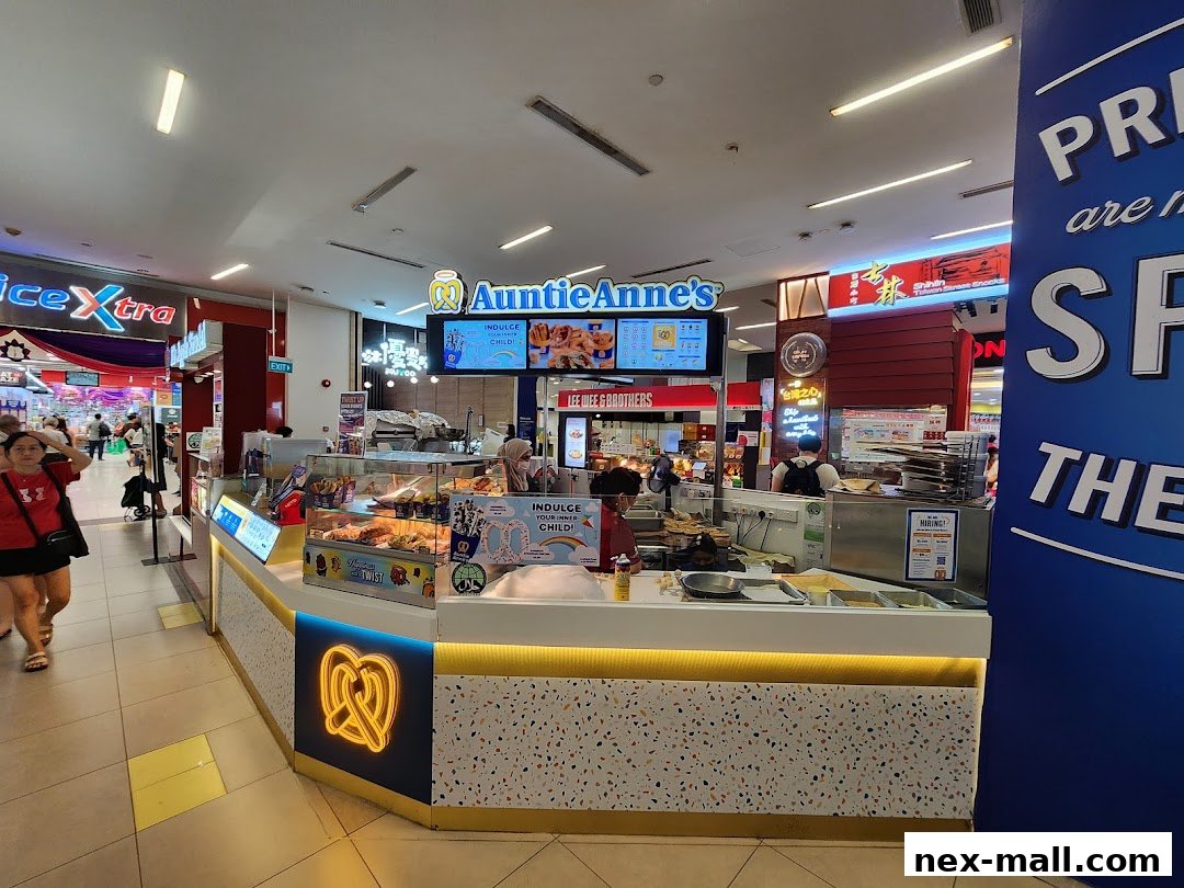 Auntie Anne's pretzel shop counter with pretzels and drinks displayed, and customers nearby.