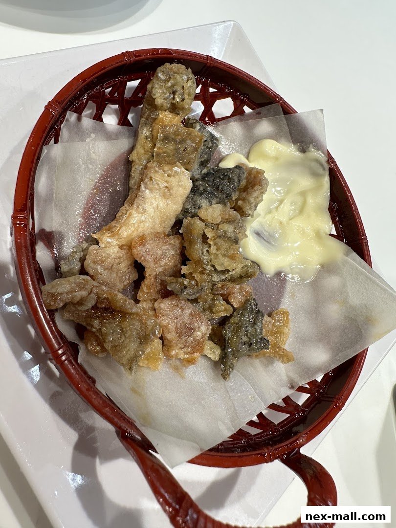 Crispy fried salmon skin served in a red basket with a side of mayonnaise.