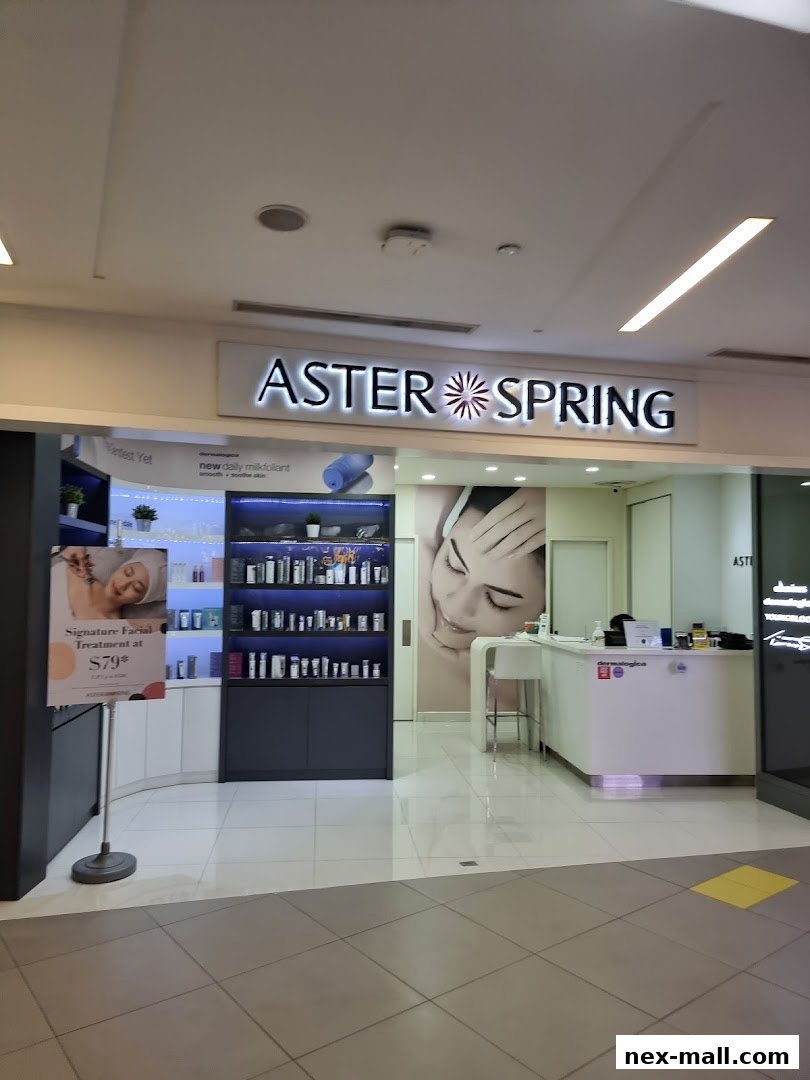 The entrance of Aster Spring NEX, showcasing skincare products and a facial treatment offer.