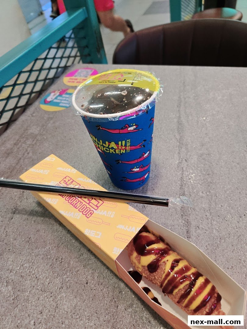 A JINJJA Chicken corn dog and drink on a table.