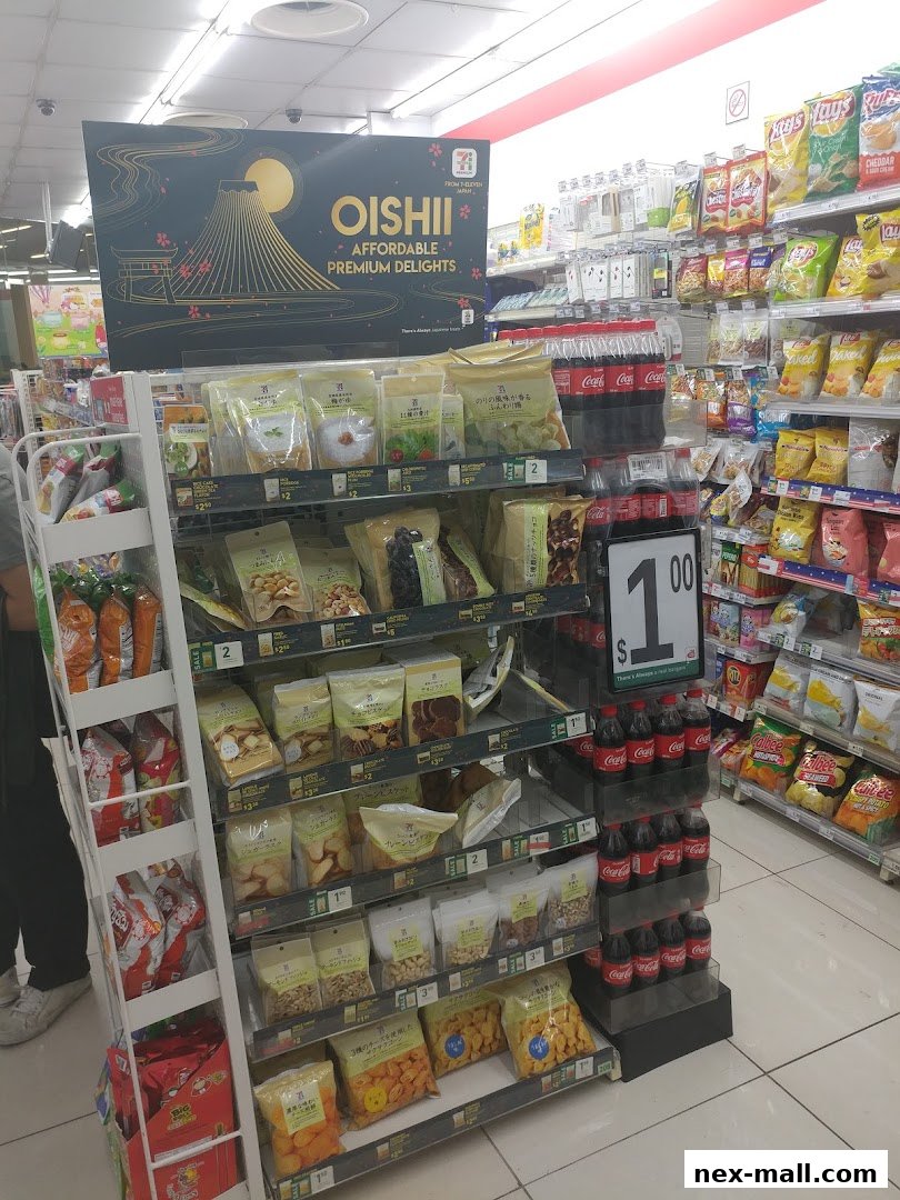 A 7-Eleven store aisle displaying various snacks, drinks, and a promotional sign for Oishii Japanese delights.