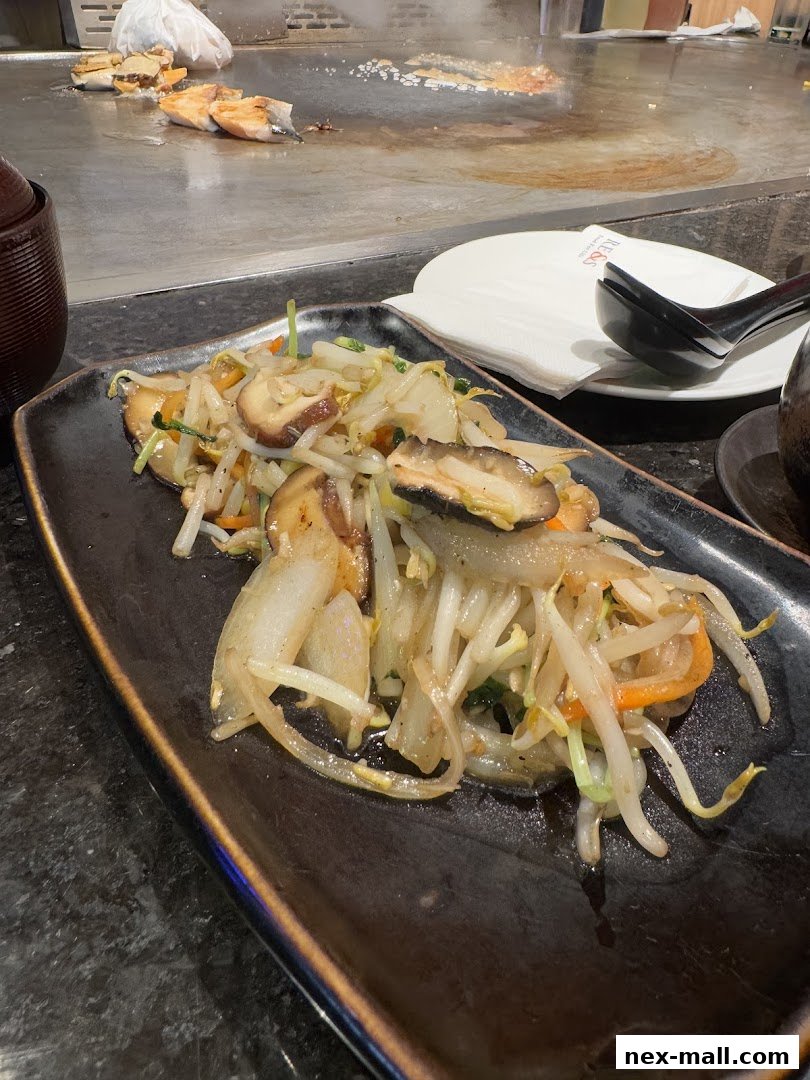 A plate of stir-fried vegetables with mushrooms and bean sprouts is served at a teppanyaki grill.