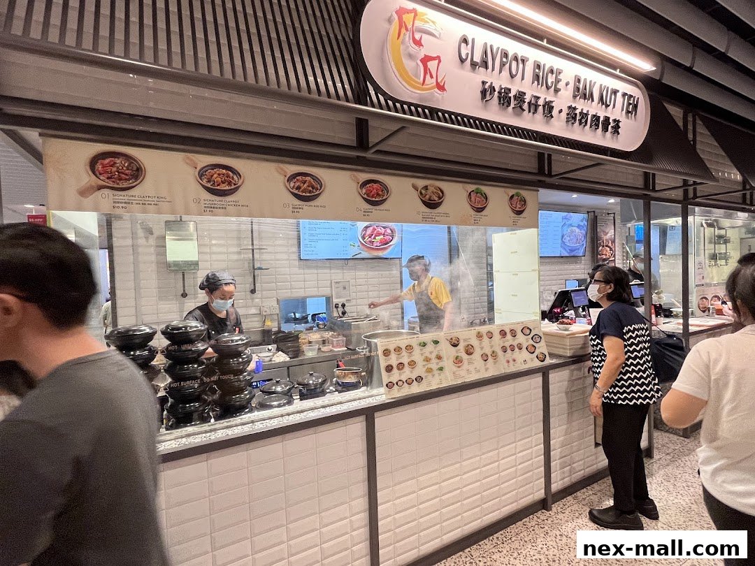 A food stall with a sign for Claypot Rice and Bak Kut Teh, showing menu items and staff preparing food.