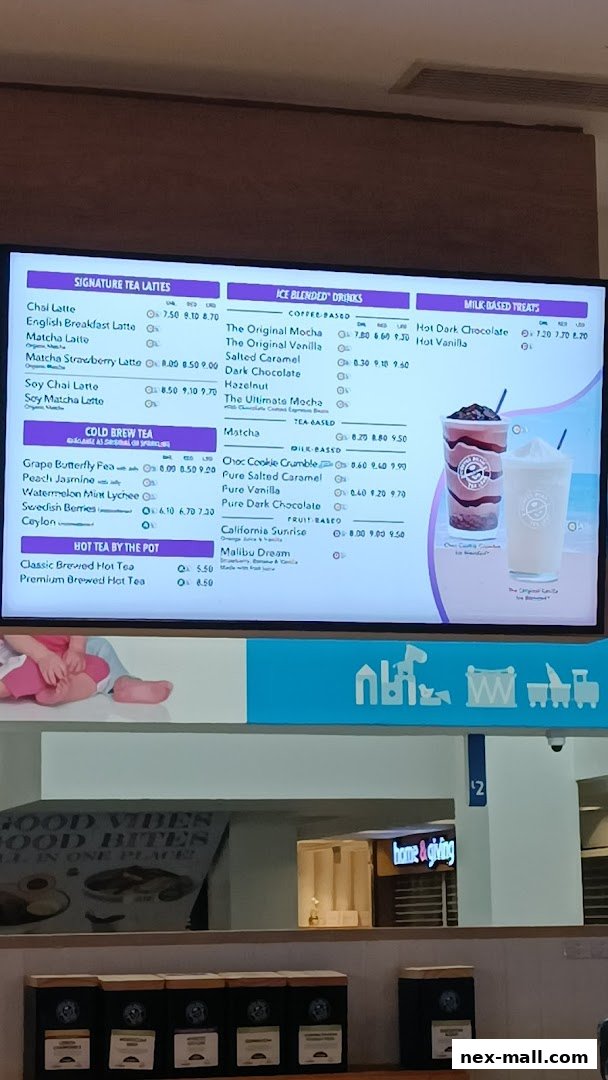 A digital menu board displaying various tea and coffee drinks with prices.