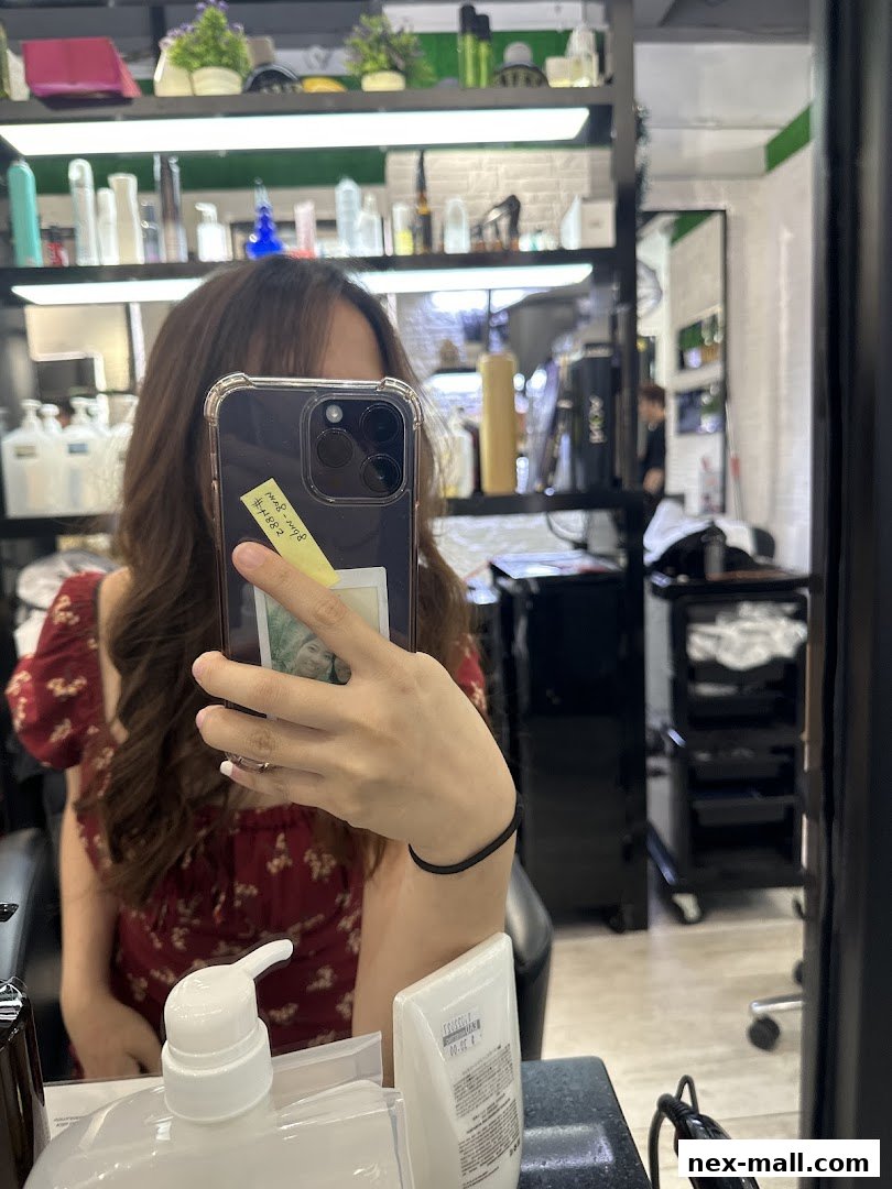A person takes a mirror selfie in a hair studio, showcasing shelves stocked with hair products.